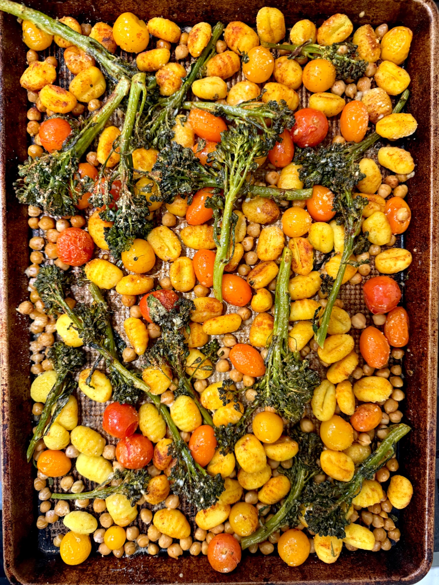 Roasted gnocchi, chickpeas, broccolini and colorful tomatoes on a sheet pan